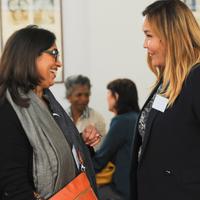 Two women facing each other smiling whilst engaged in conversation